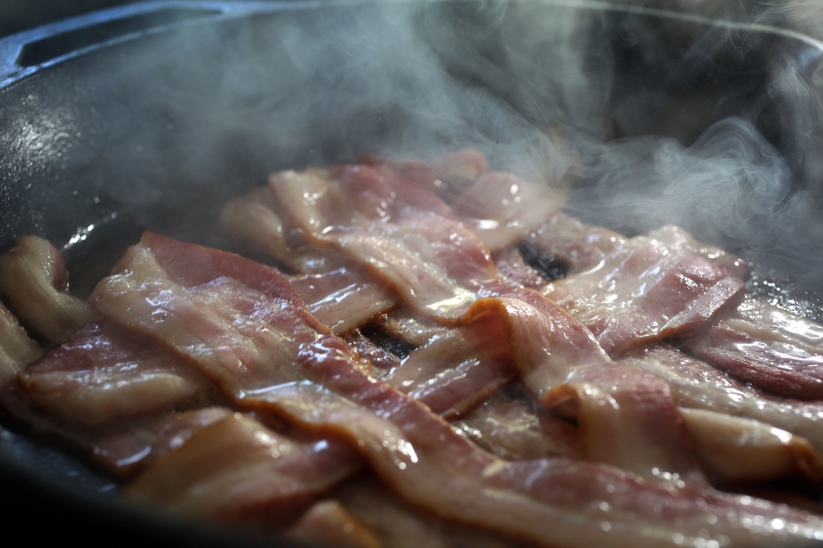 Bacon cooks in a frying pan.
