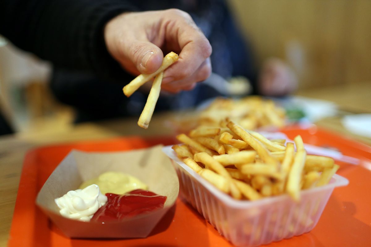 A customer dips french fries in ketchup to eat.