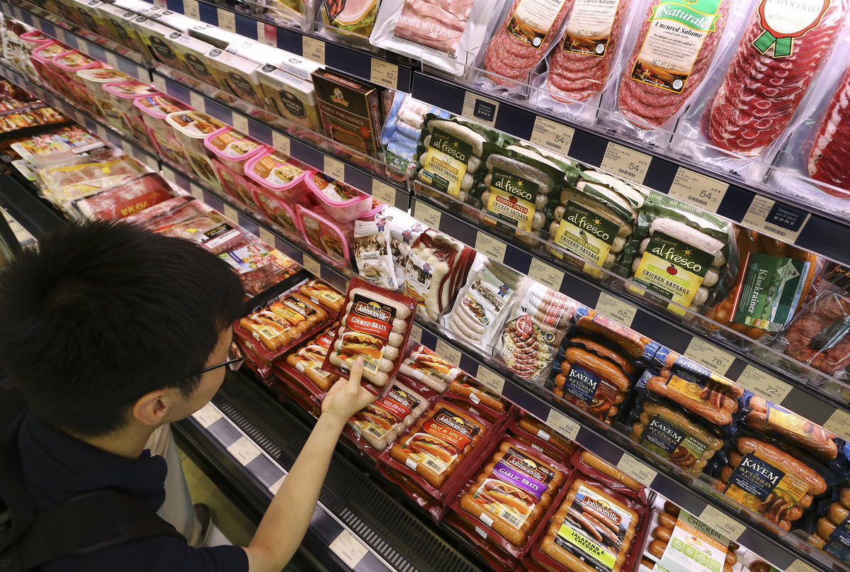A man browses packaged sausages at the grocery store.