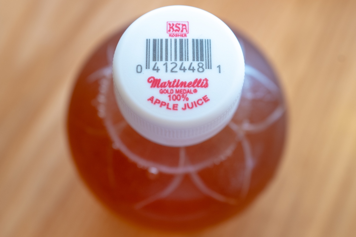 A close-up of a bottle of apple juice is seen.