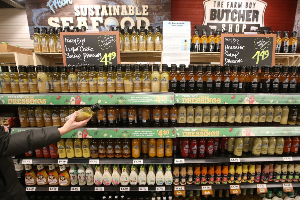 A customer browses shelves of salad dressings in a supermarket.
