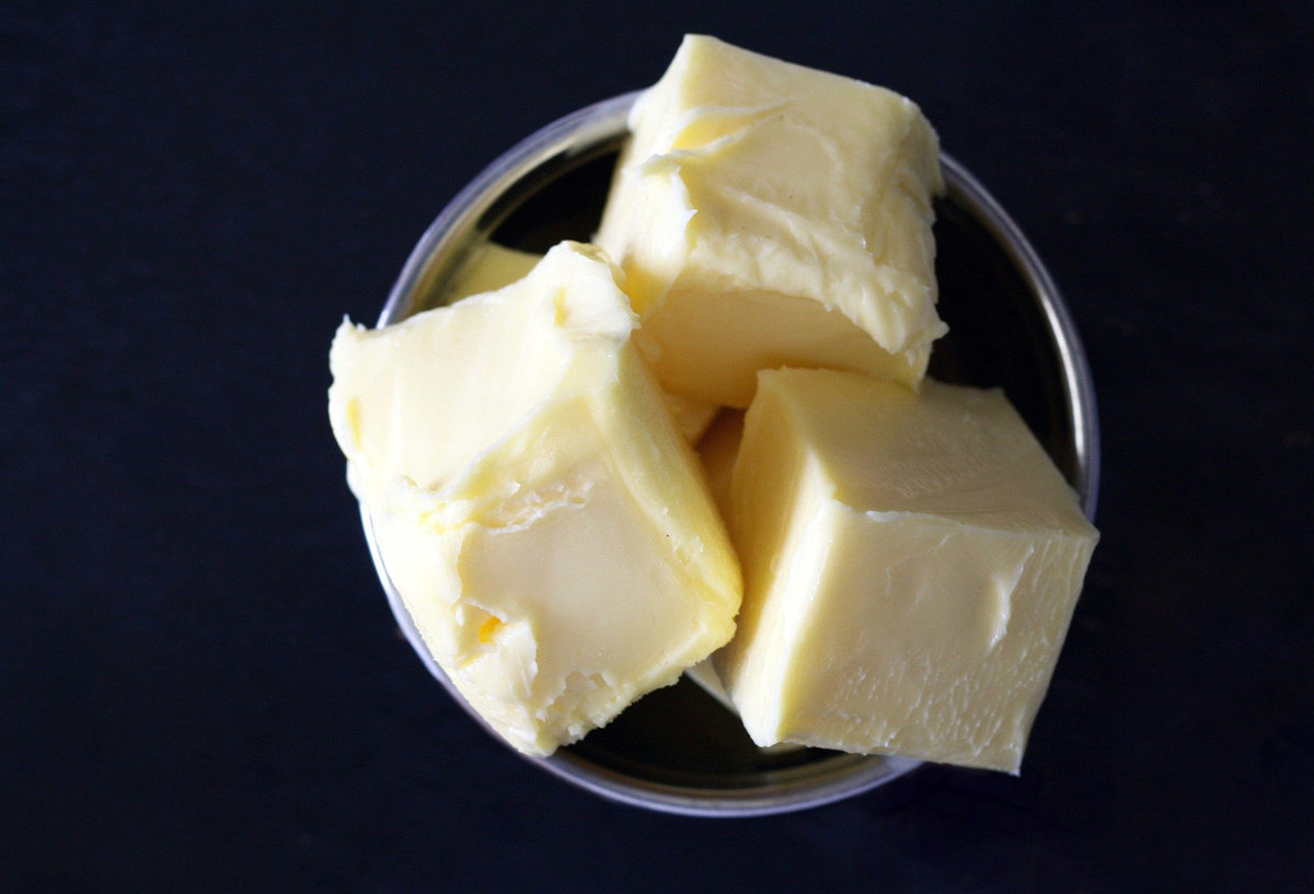 Three cubes of butter sit in a glass bowl.