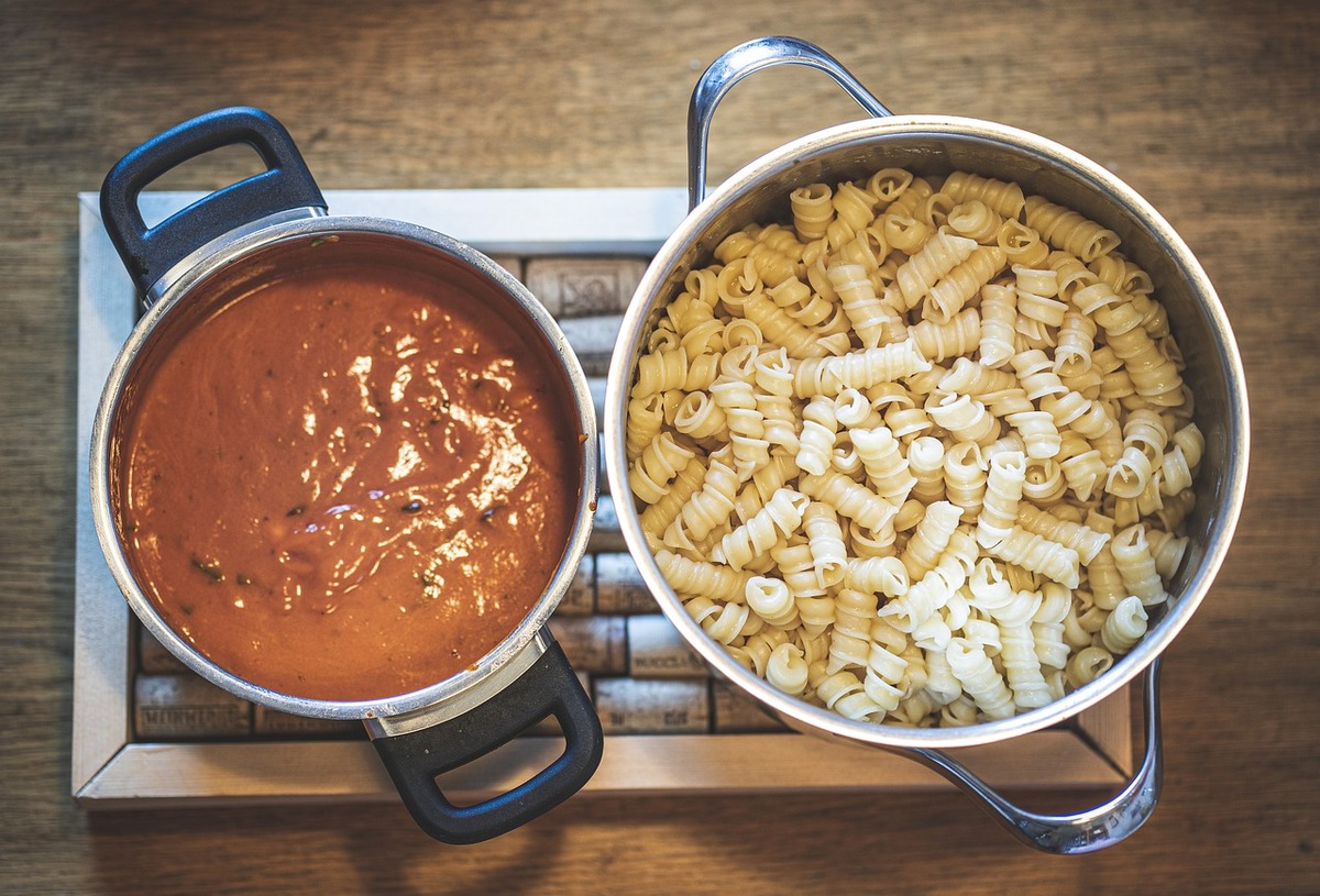 The pot on the left contains pasta sauce, while the pot on the right contains noodles.
