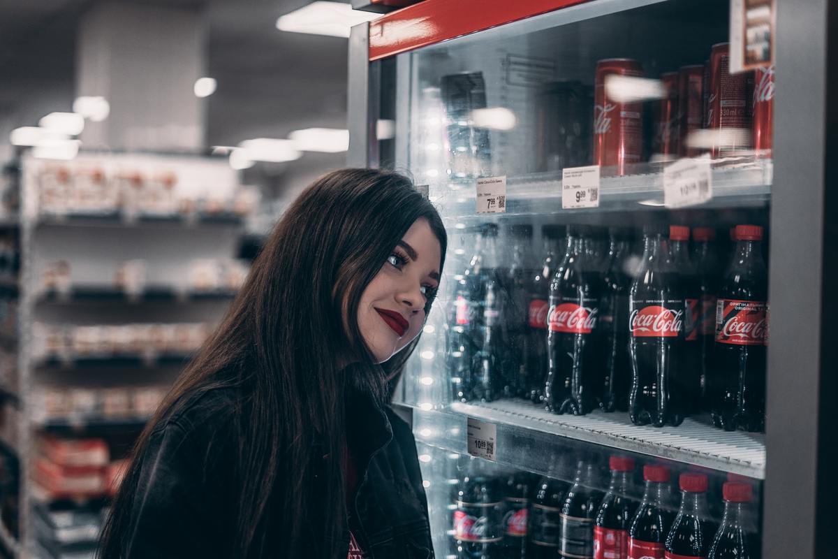 A woman browses sodas in a store.
