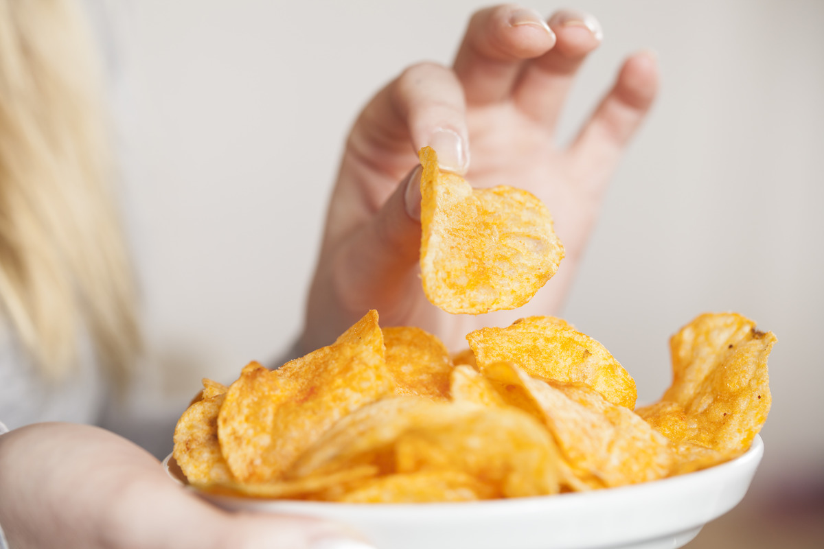 A woman picks up a potato chip.