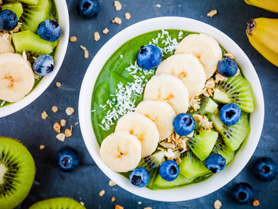 Green smoothie bowl with banana, kiwi, blueberry, granola.